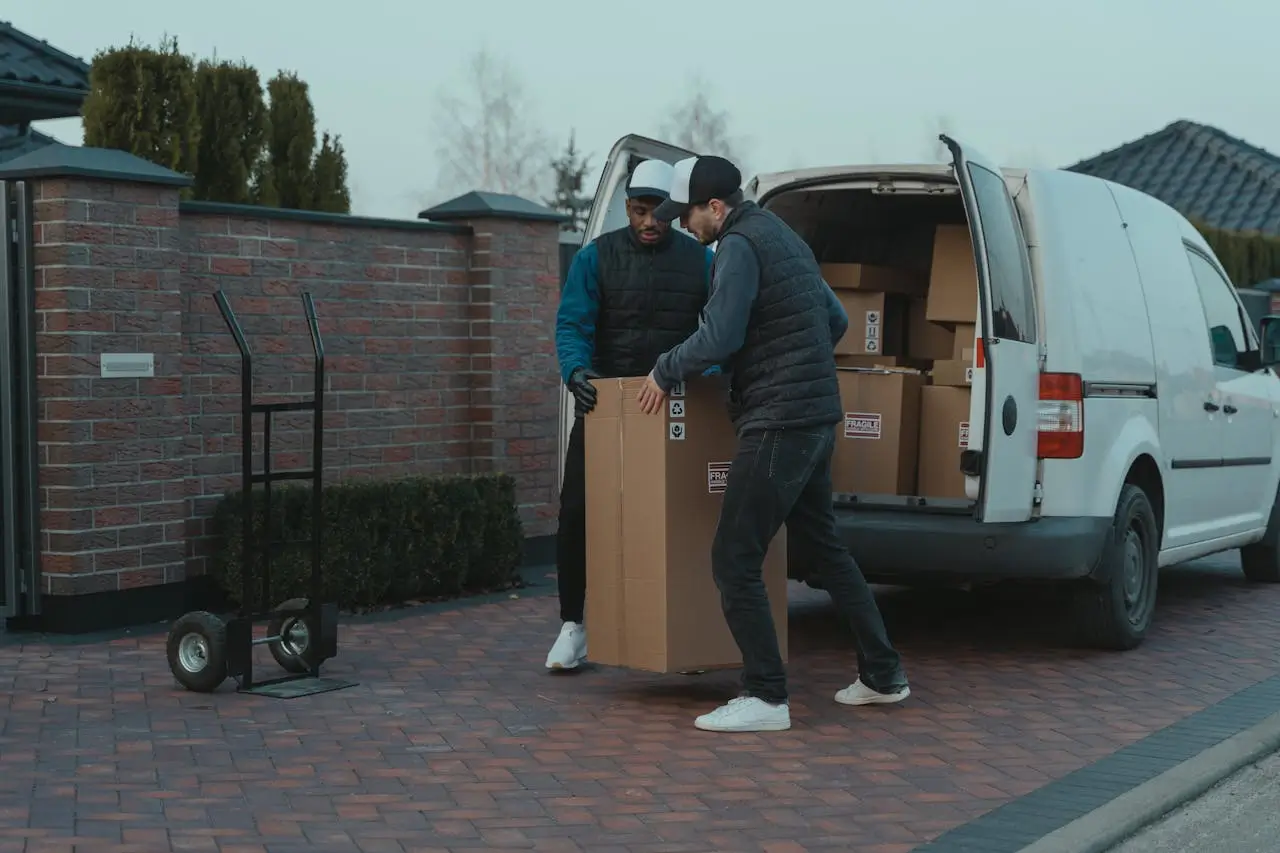 Choisir une formule de déménagement professionnelle Deux déménageurs professionnels déchargeant un grand carton fragile d'un camion blanc